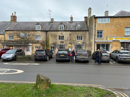 a building with cars parked in a parking lot at Siam cottage guesthouse over 300 years old with Thai restaurant in Moreton in Marsh