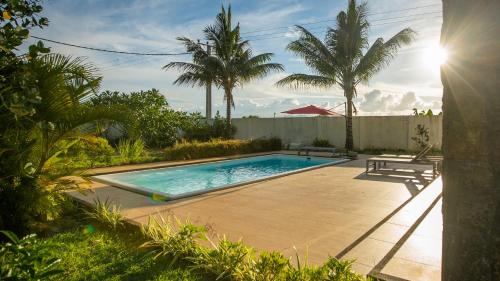 a swimming pool in a yard with palm trees at Villa Angelou - Sunlit Beach Getaway with Pool and WIFI in Belle Mare