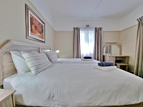 a bedroom with a large white bed and a window at Fairway Holiday Accommodation in Hermanus