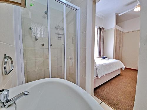 a bathroom with a shower and a bath tub at Fairway Holiday Accommodation in Hermanus