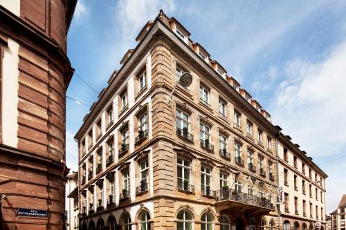 ein hohes Gebäude mit einer Uhr auf der Seite in der Unterkunft Hôtel Gutenberg in Straßburg