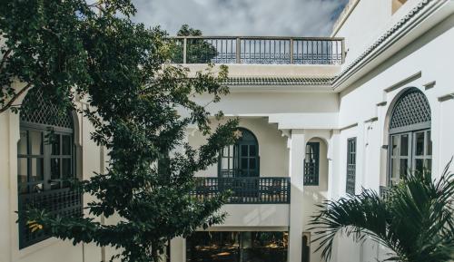 a white house with a balcony and trees at Ambre & Epices Jungle Hotel & Spa in Tulum