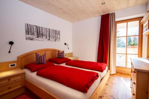 a bedroom with two beds with red pillows at Editlodge "Dessot" in Badia