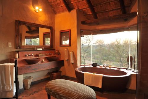 La salle de bains est pourvue de 2 lavabos et d'une grande baignoire. dans l'établissement Lukimbi Safari Lodge, à Hectorspruit