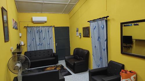 a waiting room with black furniture and a yellow wall at Homestay Opah Parit Buntar, Perak in Parit Buntar