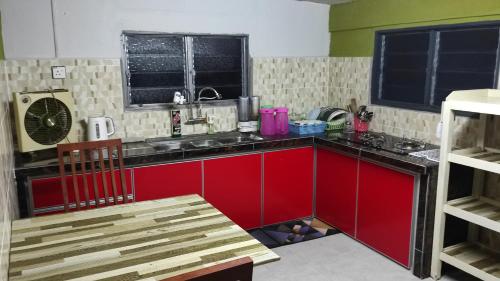 a kitchen with red cabinets and a red counter top at Homestay Opah Parit Buntar, Perak in Parit Buntar