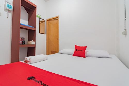 a bedroom with a white bed with a red pillow at RedDoorz near Riau Junction Mall 2 in Bandung