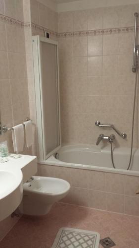 a bathroom with a tub and a toilet and a sink at Hotel Rodes in Ortisei