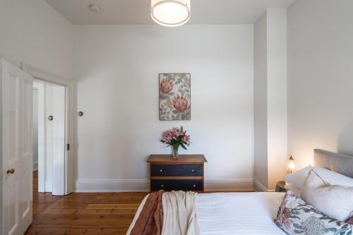 a bedroom with a bed and a vase of flowers on a dresser at The Governess in Launceston