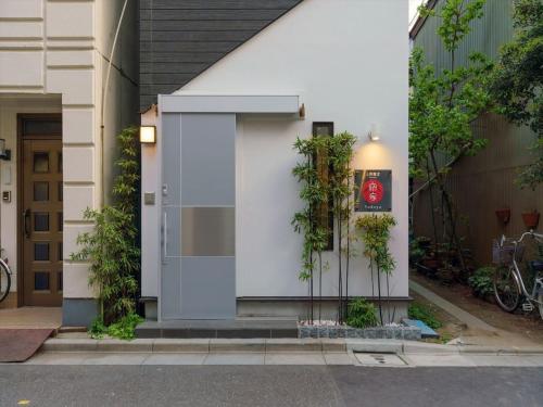 a white building with a door with plants on it at YADOYA Ueno-Rikyu in Tokyo