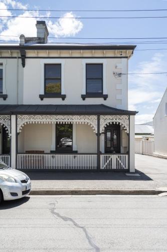a white house with a porch and a car parked in front at The Governess in Launceston