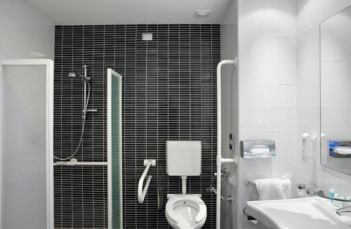 a bathroom with a shower and a toilet and a sink at Holiday Inn Milan Nord Zara by IHG in Cinisello Balsamo