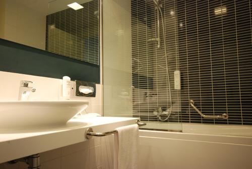 a bathroom with a sink and a glass shower at Holiday Inn Milan Nord Zara by IHG in Cinisello Balsamo