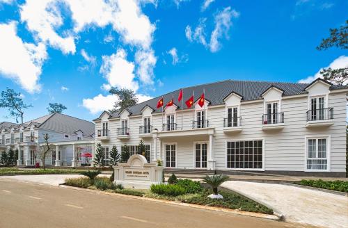 a white building with red flags on top of it at Golden Sun Hotel - Mangden in Kon Tum