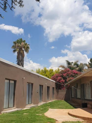 a house with a palm tree in the background at Rose Guesthouse Klerksdorp in Klerksdorp