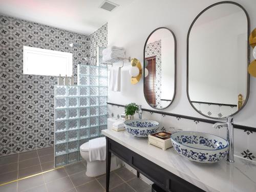 a bathroom with two blue and white sinks and mirrors at Golden Sun Hotel - Mangden in Kon Tum