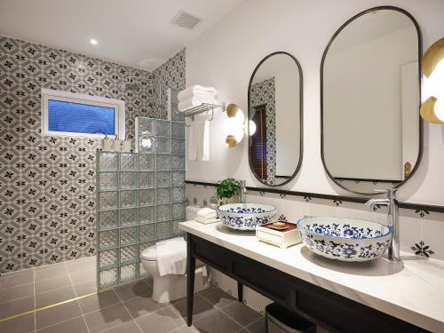 a bathroom with two sinks and two mirrors at Golden Sun Hotel - Mangden in Kon Tum