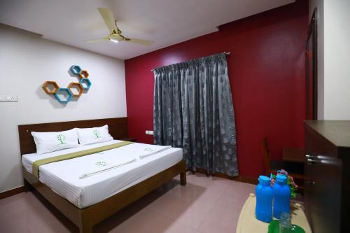 a bedroom with a bed and a red wall at The Ideal Nest Kumbakonam in Kumbakonam