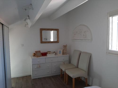 Cette chambre comprend un miroir, une chaise et une commode. dans l'établissement Location maison 4 pers Le Grau d'Agde 34, au Grau-dʼAgde