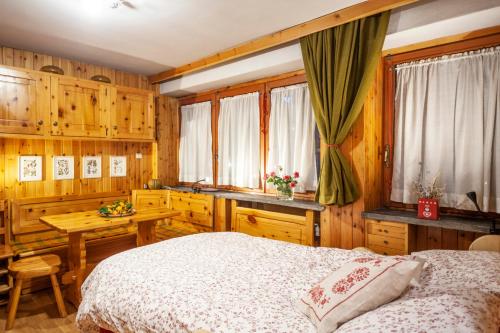 Un dormitorio con una cama y una mesa y ventanas. en Casa-chalet, in centro a Courmayeur!, en Courmayeur