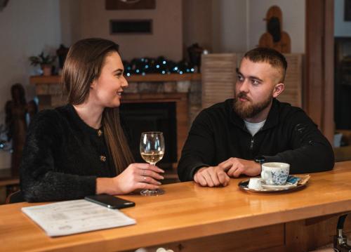 a man and woman sitting at a table with a glass of wine at Penzión Solisko*** Oščadnica in Oščadnica