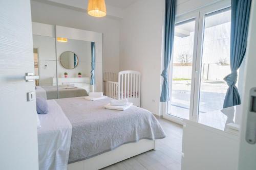 een witte slaapkamer met een bed en een groot raam bij Villa Smile in Ližnjan
