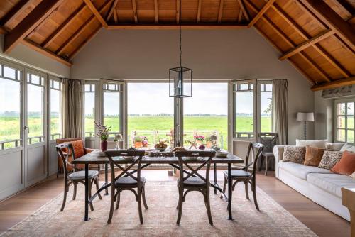 a dining room with a table and chairs and a couch at B&B De Hemelse Polder in Sint-Laureins