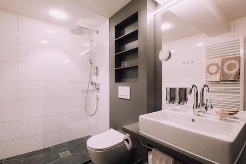 a white bathroom with a sink and a toilet at Naturhotel Chesa Valisa in Hirschegg