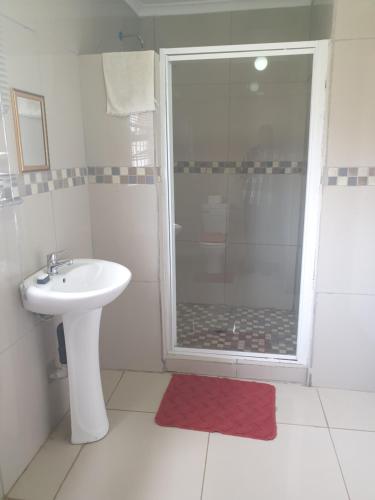 a white bathroom with a shower and a sink at Rose Guesthouse Klerksdorp in Klerksdorp