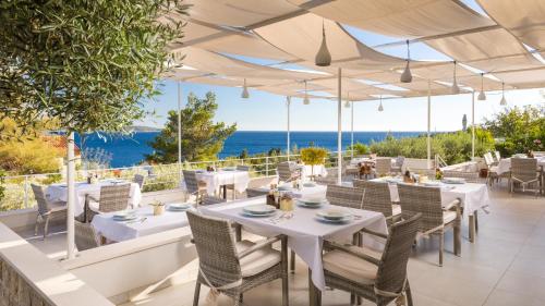 a restaurant with white tables and chairs and the ocean at Stella Mare Eco Boutique House in Zavala