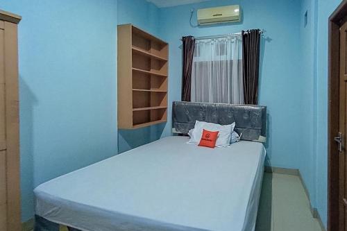 a blue room with a bed with a red book on it at KoolKost Syariah At Komplek PLN Balikpapan in Balikpapan