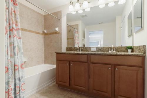 a bathroom with a sink and a tub and a mirror at Townhome w pool near Disney & Orlando Attractions in Kissimmee