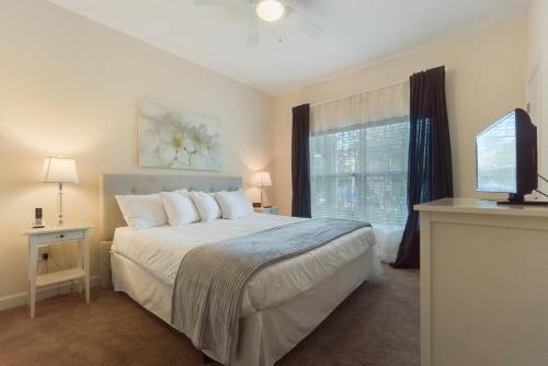 a bedroom with a bed and a television and a window at Townhome w pool near Disney & Orlando Attractions in Kissimmee