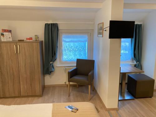 a room with a chair and a desk and a window at Pension Lachmann in Pfaffendorf
