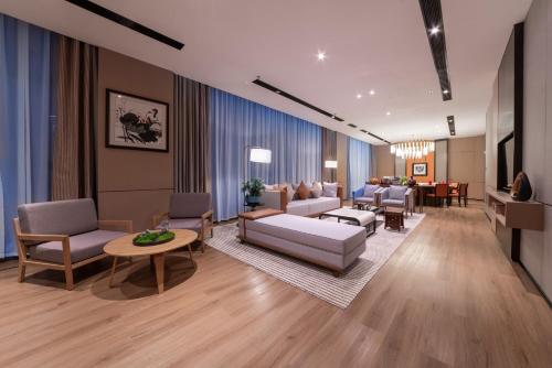 深セン市にあるHoliday Inn Express Shenzhen Longhua by IHGのソファと椅子とテーブルのあるリビングルーム
