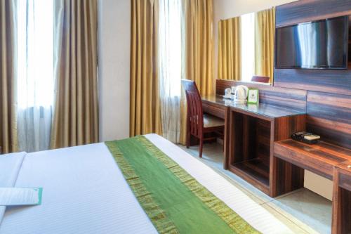 a hotel room with a bed and a desk with a television at Hotel Dreamland Chandigarh in Chandīgarh