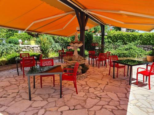 een patio met tafels en stoelen onder een oranje parasol bij La casa color in Lamagdelame