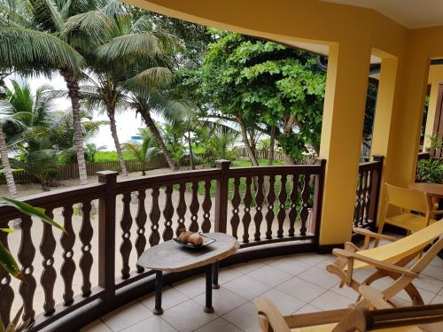 a balcony with a table and chairs and palm trees at Pieds Dans L’Eau Holiday Apartments in Mahe
