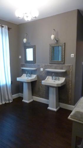 une salle de bain avec deux lavabos et un grand miroir dans l'établissement Le Logis Alexandra BnB, à La Trimouille