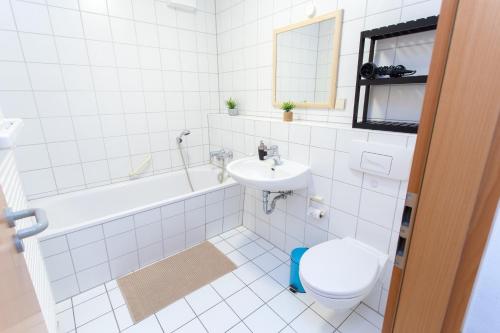 Baño blanco con aseo y lavamanos en FULL HOUSE Studios - Kornhaus Classic Apartment, en Dessau