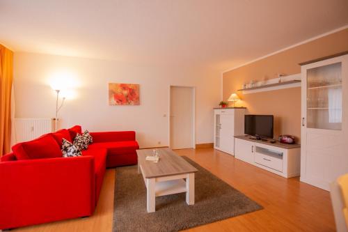 sala de estar con sofá rojo y mesa en Ferienwohnung Sanddorn - Strandhaus Lobbe, en Lobbe
