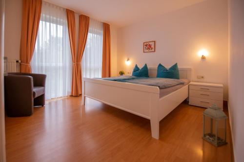 ein Schlafzimmer mit einem großen weißen Bett mit blauen Kissen in der Unterkunft Ferienwohnung Sanddorn - Strandhaus Lobbe in Lobbe