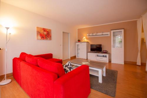 sala de estar con sofá rojo y mesa en Ferienwohnung Sanddorn - Strandhaus Lobbe, en Lobbe