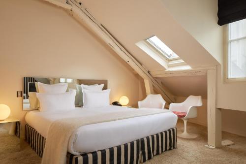 a bedroom with a large bed and a skylight at Hôtel du Petit Moulin, Haute Couture hotel by Lacroix in Paris