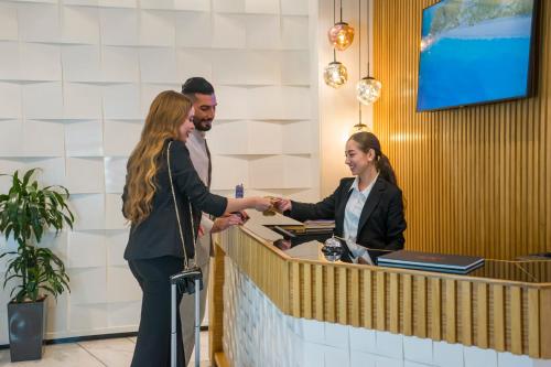 a man and woman shaking hands at a counter at Flamant Rose Appart Hotel in Tangier