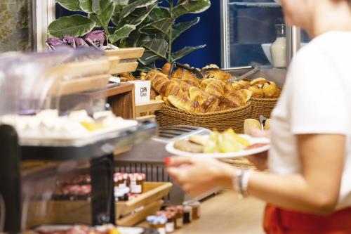 a woman is holding a plate of food in a bakery at Hotel Les Suites - Domaine de Crécy in Crecy la Chapelle