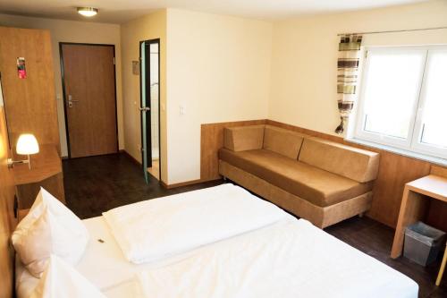 een hotelkamer met een bank en een bed bij Hotel Cafe Kern in Großostheim