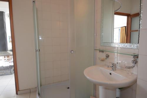 a bathroom with a sink and a shower with a mirror at Aina Hôtel in Antananarivo