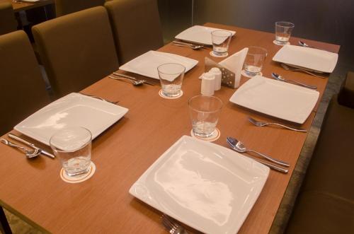 a wooden table with empty plates and glasses on it at Hotel Comfotel Kolkata in Kolkata