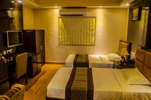 a hotel room with two beds and a television at Hotel Comfotel Kolkata in Kolkata